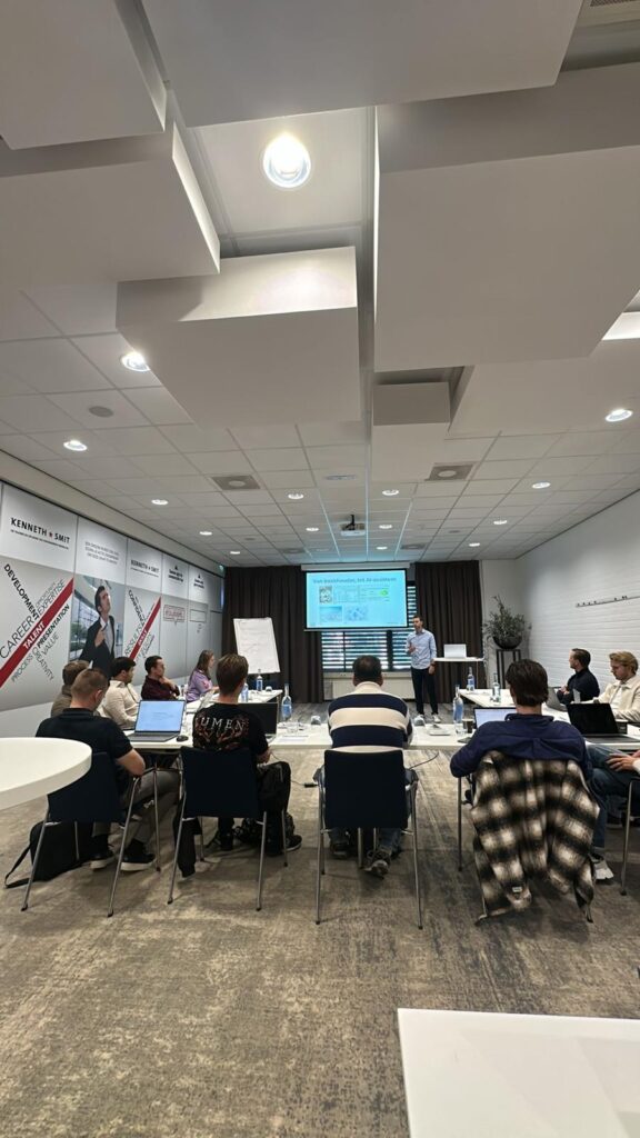 Een live AI-workshop van Lumans in een presentatieruimte, waar deelnemers achter laptops luisteren naar een presentatie met de titel 'Van boekhouder tot AI-assistent'.